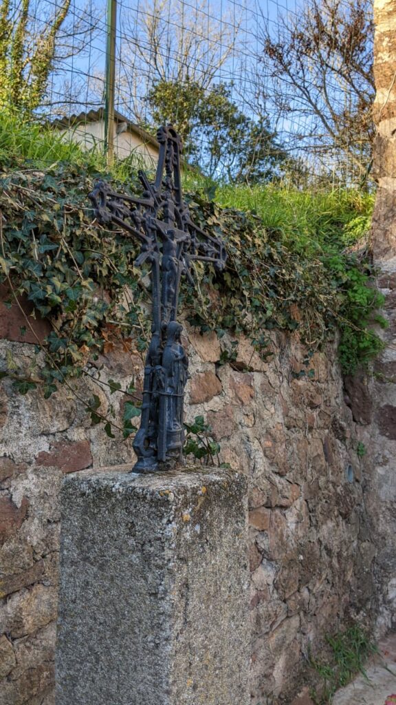 Une croix métallique (hauteur environ 50cm) peinte en noire avec un christ crucifié. La croix est fixée sur un plot de béton (hauteur du plot environ 1mètre). Une vierge, fait dans le même métal noir, à été accroché avec du fil de fer au pied de la croix.