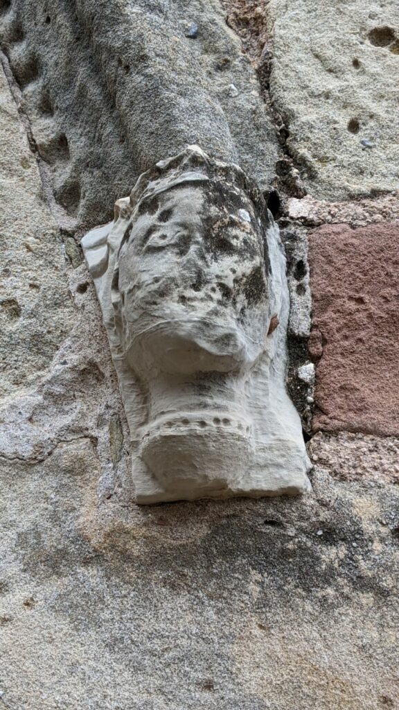 Tête sculpté possiblement d'origine wisigoth, d'environ 20 cm de haut servant de culot sous l'arche du portail de l'église Ste Marie de Frangouille. Visage abîmé par le temps