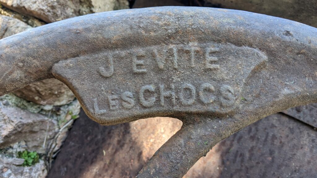 Vue sur l'inscription "J'évite les chocs" gravée sur le volant de la roue d'une pompe à eau