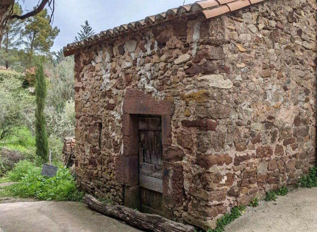 Au bout d'une impasse, une construction en pierre avec 2 côtés visibles. Sur une face, une petite et vieille porte en bois. On devine le toit à une pente.